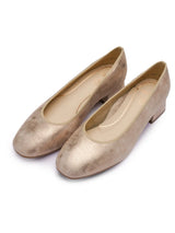Pair of metallic gold flats on a white background