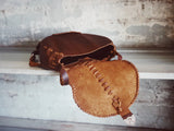 Brown leather bag with decorative stitching on a textured surface