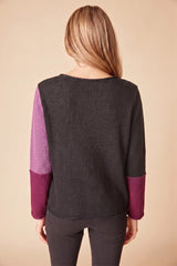 Back of a woman wearing a blackand purple color-blocked sweater on a beige background