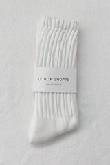 A single white ribbed knit ballet sock with a paper band label reading 'LE BON SHOPPE BALLET SOCKS', laid flat on a light fabric background.