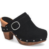 A black suede clog shoe with a chunky wooden block heel, silver metal studs, and a wide strap with a silver buckle, shown on a white background.