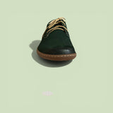 Green shoe with brown sole on a light green background