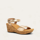 Gold wedge sandal with cork sole on a light gray background