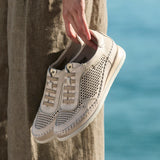 Person holding a beige sneaker with a textured pattern against a blurred natural background