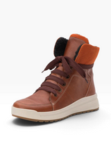 A brown leather high-top winter boot with dark brown laces, a thick off-white midsole, and a bright orange collar lining with black faux-fur trim, shown on a white background.