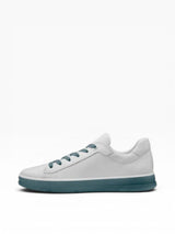 White sneaker with blue sole on a light gray background