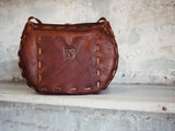 Brown leather bag with visible stitching on a wooden surface