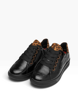 A pair of black low-top sneakers with a glossy textured leather finish, black laces, and a brown leopard print lining visible at the collar, shown on a white background.