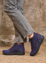 Person wearing purple and gray pants with a tan background