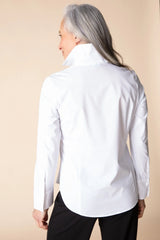 Person wearing a white shirt with long sleeves on a beige background