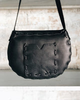 Black leather handbag with visible stitching on a neutral background