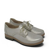 Pair of light gold leather shoes with brown soles on a white background