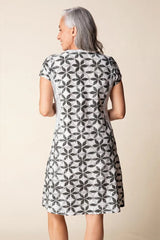 Woman wearing a patterned dress against a plain background