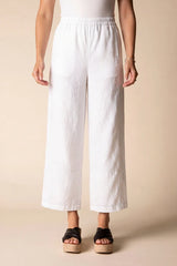 Person wearing white wide-leg pants on a beige background