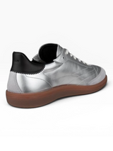 Silver sneaker with black heel and brown sole on a white background