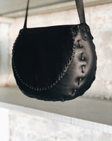 Black leather handbag with textured surface on a neutral background