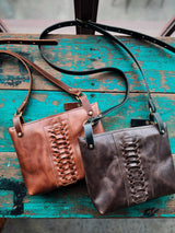 Two leather handbags, one brown and one dark brown, on a rustic wooden surface.