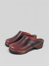 Pair of brown leather clogs on a light gray background