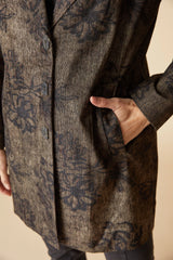 Close up of a woman wearing a black floral pattern on an umber colored car coat