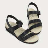 Black sandals with multiple straps on a light gray background
