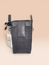 Grey textured crossbody bag with a tag on a beige background