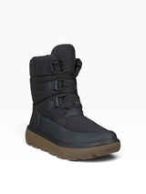 A black mid-calf winter boot with a thick brown lug sole, featuring hook-and-loop strap closures on the side, shown against a plain white background.