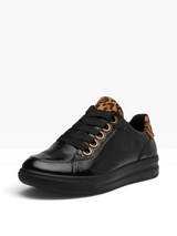 A black low-top sneaker with a textured leather finish, black laces, and a brown and black leopard print lining on the tongue and heel, shown against a plain white background.