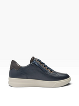 A navy blue leather low-top sneaker with a thick cream-colored sole, dark brown heel tab, and metallic gold eyelets, shown from a side profile on a white background.