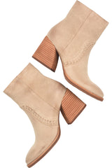 A pair of beige suede ankle boots with stacked brown block heels and decorative stitching on the sides, shown against a plain white background.