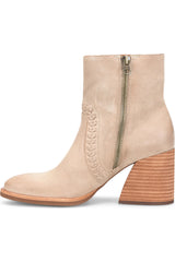 A light beige suede ankle boot with a chunky stacked wood-look block heel, a side zipper, and decorative stitching on the side.