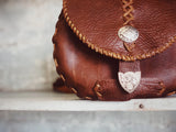Brown leather bag with decorative elements on a neutral background