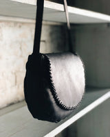 Black leather handbag hanging on a shelf with a blurred background