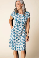 Woman wearing a blue floral patterned dress against a beige background