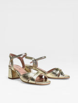 Gold high-heeled sandals on a white background
