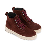 A pair of mid-calf suede boots in a deep burgundy brown, featuring matching burgundy laces, silver metal eyelets, and a thick cream-colored lug sole, shown against a plain white background.