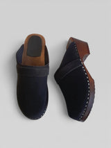 Pair of black oiled leather clogs with brown soles on a light gray background