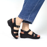 Black sandals worn with blue jeans on a white background