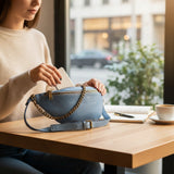 Bue leather medium sling bag with adjustable strap and antique bronze chain detail. Features zip pockets.