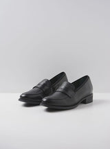 Pair of black leather loafers on a light gray background